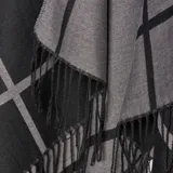Poncho de tejido de punto con diseño de cuadros grandes en contraste negro y gris, con terminación de flecos en el ruedo.
