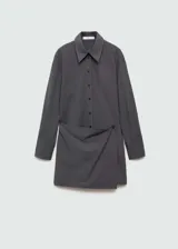 Vestido corto de estilo camisero con diseño cruzado, cuello clásico y cierre frontal de botones. Presenta mangas largas con puños abotonados y un sutil estampado de raya diplomática.