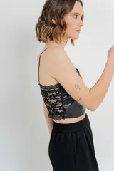 Top crop negro de cuero ecológico con espalda de encaje floral nude, tirantes finos y corte entallado.