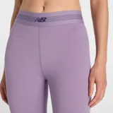 Calza deportiva New Balance de tiro alto, color lila, con banda elástica en la cintura que presenta el logo de la marca. Confeccionada en tejido elástico de alta intensidad.