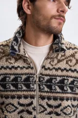 Buzo de sherpa con medio cierre frontal, cuello alto y estampado geométrico abstracto en tonos beige, marrón y negro.