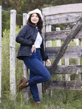 Pantalón de jean chupín azul oscuro con costuras marcadas al frente y detalle de botones dorados en los tobillos.