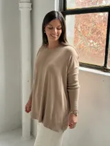 Sweater de punto color visón con cuello redondo, mangas largas con puños acanalados y diseño holgado con detalle de costura vertical central.