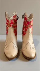 Botas de cuero estilo texano color natural, con caña corta decorada con un diseño artístico de cuadrados en tonos coral, fucsia y marrón. Presentan costuras decorativas en la puntera y un taco cuadrado de madera.