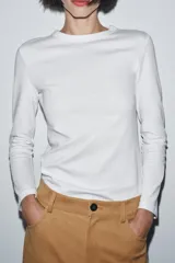Camiseta de manga larga confeccionada en tejido de punto interlock elástico y flexible, con cuello redondo y bajo recto.