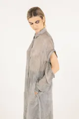 Camisa larga o vestido camisero de viscosa y seda, color gris con efecto teñido en frío, de tejido semitransparente, cuello clásico, mangas largas desmontables y cierre frontal con botones.