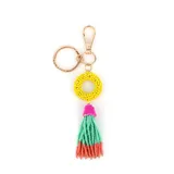 Llavero con argolla y mosquetón metálicos dorados, compuesto por un aro central de mostacillas amarillas y un colgante de borla con mostacillas en colores fucsia, verde agua y coral.