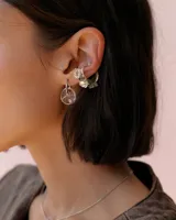 Earcuff de acrílico compuesto por una estructura circular con tres flores incrustadas decorativas.