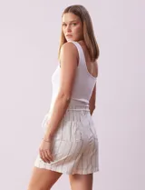 Short color crema con finas rayas verticales grises, pretina elastizada con cordón de ajuste, bolsillos delanteros y traseros.