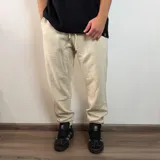 Pantalón tipo jogger de friza de algodón en color beige, con cintura elástica ajustable mediante cordón y puños elásticos en los tobillos. Presenta un calce holgado y cómodo.
