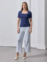 Buzo azul de tejido acanalado, con escote cuadrado y aplique de botones.