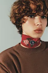 Choker de tela semitransparente color bordó con bordado floral multicolor en el centro y cierre mediante lazada ajustable con cordón negro.