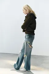 Jeans de tiro bajo y corte recto, color celeste con efecto lavado. Presenta diseño de doble tiro con detalle de short superpuesto con roturas, además de roturas adicionales en las perneras. Cuenta con cinco bolsillos, trabillas para cinturón y cierre frontal con cremallera y botón metálico.