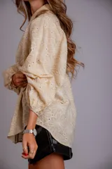 Camisa de manga larga con diseño abullonado, confeccionada en tela bordada con motivos florales. Presenta cierre frontal con botones y puños elásticos.