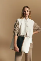 Chaleco de paño color marrón oscuro, de silueta recta y diseño minimalista. Presenta cuello a la base, cierre frontal con botones claros y bolsillos aplicados.