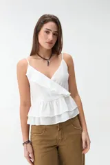 Musculosa blanca de tirantes finos, con escote en V cruzado y detalle de volados en el escote y en el ruedo con diseño de capas.