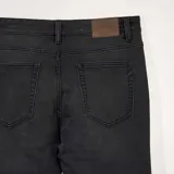 Pantalón de jean gris oscuro, corte slim, con bolsillos delanteros y traseros.