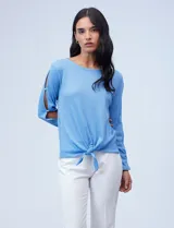 Blusa tejida color celeste con lurex, de manga larga con aberturas y apliques de brillo. Ruedo anudado.