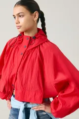 Campera parka roja estilo blouson con capucha ajustable, cierre frontal de botones a presión, bolsillos frontales con solapa y diseño holgado.