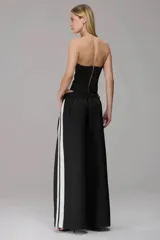 Pantalón wide leg de color negro con franjas laterales blancas, corte de tiro medio, cintura con cordón ajustable y pinzas frontales que aportan volumen y caída fluida.