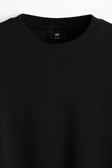 Remera negra de punto de algodón pesado, corte boxy holgado, con cuello redondo ribeteado acanalado, hombros caídos y bajo recto.