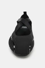 Bailarina deportiva negra, confeccionada con una combinación de malla, gamuza sintética y material elástico, con tiras cruzadas en el empeine.