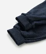 Pantalón de pijama tipo jogger color azul marino, con cintura elástica y cordón de ajuste. Presenta puños elásticos en los tobillos y un acabado jaspeado.