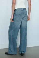 Jeans de tiro medio con diseño baggy barrel, cinco bolsillos y costuras laterales curvadas. Presenta cierre frontal con cremallera y botón metálico.