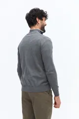 Sweater de tejido liso color verde oscuro, con cuello medio y cierre frontal parcial plateado. Presenta puños y cintura acanalados, y un pequeño logo bordado en el pecho.