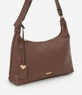 Cartera mediana tipo hobo de Satinato, confeccionada en poliuretano con textura granulada y diseño geométrico sutil. Cuenta con cierre superior de cremallera, correa de hombro ajustable y un dije decorativo metálico con forma triangular.