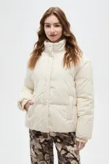 Campera puffer de corte holgado, color crema, con cuello alto, cierre frontal oculto y puños tejidos acanalados.