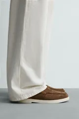 Mocasines casuales para hombre, fabricados en piel con acabado en serraje color marrón, de corte liso con detalle de bordón y suela blanca a contraste.