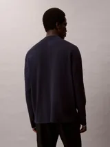 Sweater de corte boxy confeccionado en tejido de punto técnico, con cuello semi alto y mangas largas. Presenta un diseño minimalista y relajado con acabado liso.
