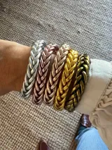 Pulsera de resina flexible con diseño trenzado y acabado brillante, con relleno de lámina metálica en tonos dorados, plateados y cobrizos.