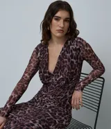 Vestido midi de manga larga confeccionado en tule con estampado animal print. Presenta un escote en V profundo, corte ajustado al cuerpo y diseño con transparencia.