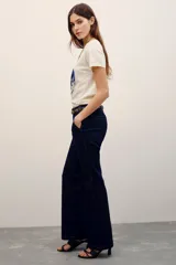 Pantalón sastrero de denim azul oscuro con costuras pespunteadas a contratono. Cuenta con cierre metálico frontal, gancho sastrero y botón en la cintura.