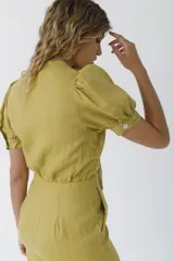 Mono negro de lino con escote pronunciado en V y nudo frontal que deja ver un corte en la cintura. Mangas cortas abullonadas y pantalón de corte recto.