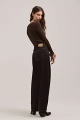 Pantalón de jean de corte wide leg en color negro, con costuras en contraste color ocre, tiro alto y cierre frontal con botón metálico.