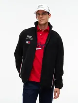 Campera de tejido polar negra Tommy Hilfiger, con cuello chimenea y cierre de cremallera. Presenta diseño Global Stripe en los laterales, bolsillos abiertos en diagonal y el logo de la marca junto con el de Cadillac Formula 1 Team en el pecho.