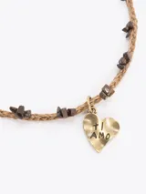 Gargantilla de hilo trenzado color celeste con pequeñas piedras incrustadas a lo largo, cierre de cadena dorada con mosquetón y un dije colgante en forma de corazón marrón con detalles grabados.