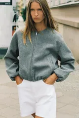 Chaqueta bomber de cuello redondo y manga larga con diseño holgado. Presenta cierre frontal con cremallera, bolsillos delanteros de vivo y acabados elásticos en los puños y el ruedo.