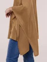 Poncho de calce holgado color marrón, confeccionado en tejido fino de punto suave, con cuello redondo y diseño de caídas laterales amplias de ruedo asimétrico.