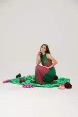 Vestido largo de microtul elastizado y lycra color verde con estampado de plumerillo en tonos rosa, amarillo y naranja. Tiene cuello americano y corte acampanado.