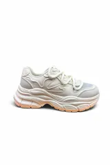 Championes deportivos chunky color blanco con suela gruesa y detalles en tono anaranjado en la parte inferior, con cordones gruesos estilo cuerda.