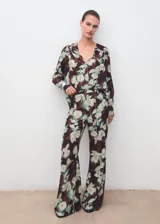Pantalón largo estilo flare de tiro medio, con cintura elástica y forro interior, con estampado floral en tonos oscuros y verdosos.