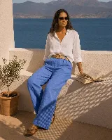 Pantalón de lino azul, de corte ancho y relajado, con cintura elástica y cinto de rafia desmontable con hebilla circular.