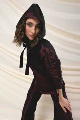 Capucha deportiva color borgoña, confeccionada en tafeta tornasolada. Se ajusta con dos tiras que pueden anudarse formando un lazo.