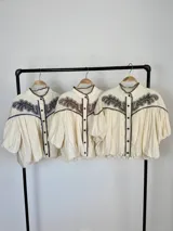 Blusa de algodón off white con cuello mao, botones frontales y mangas globo. Cuenta con canesú destacado con bordado floral en color azul marino.