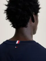 Remera azul marino de algodón con corte slim, cuello redondo y mangas cortas con ribete rojo y blanco. Logo de Tommy Hilfiger bordado en el pecho.