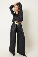 Pantalón palazzo negro de tela laminada con cintura elastizada.